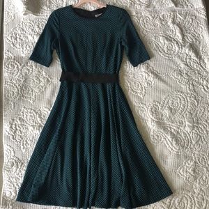 A black midi dress with dark green polka dots